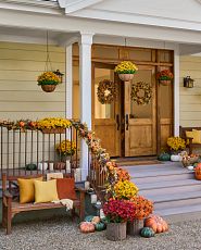 Front porch décor with fall foliage, pumpkins, and outdoor seating