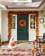 Front porch decorated with fall foliage and ghost dog Halloween decoration
