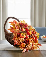 Cornucopia with apples and fall leaves on table