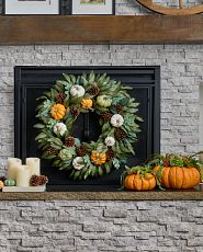 Pumpkin wreath next to pumpkin décor and candles